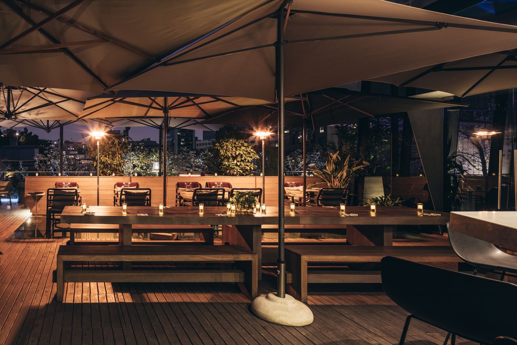 Rooftop Magnolia à noite, com mesas sob grandes ombrelones e iluminação acolhedora