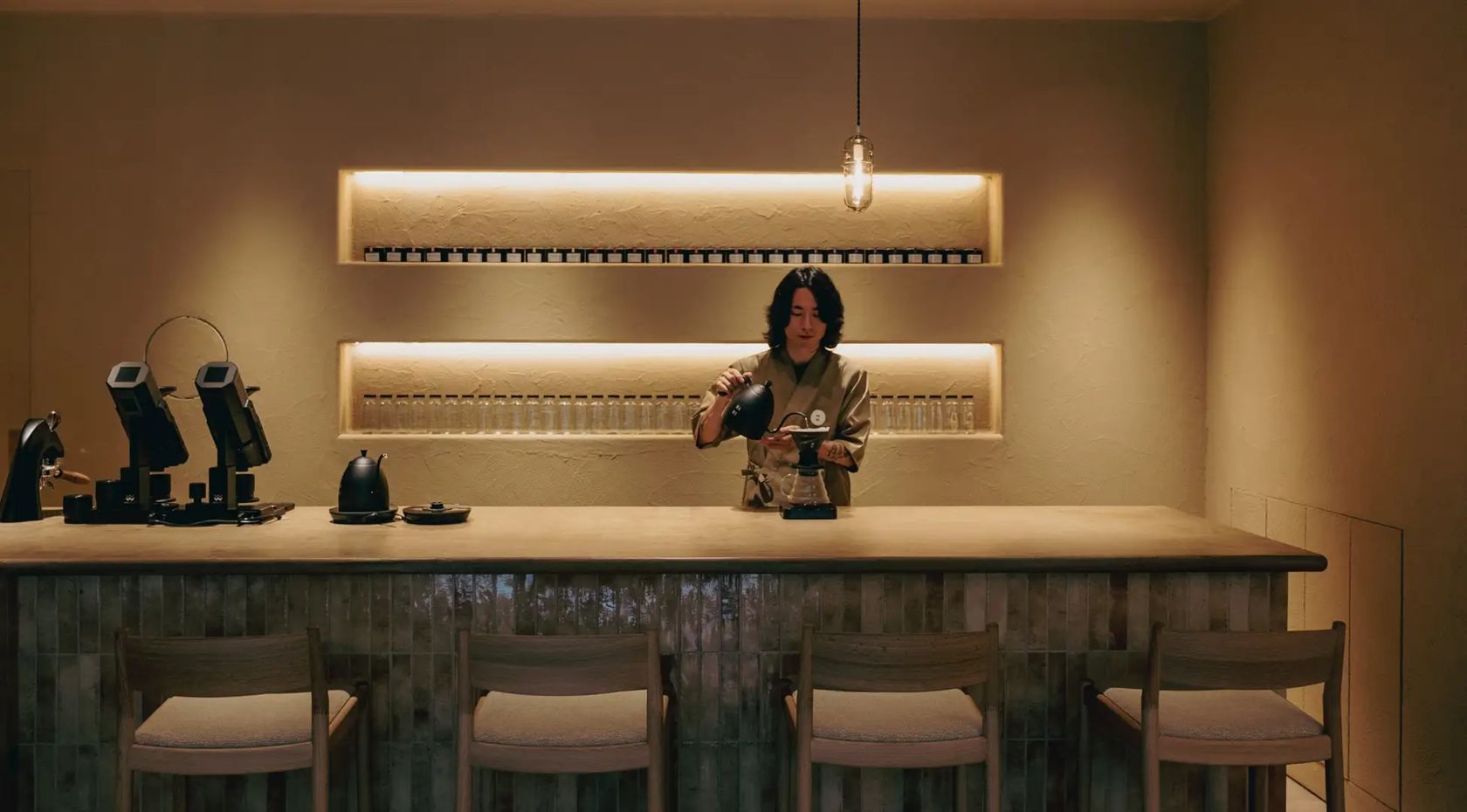 Barista preparando café diante do balcão da Kuro Mame Tokyo, em Toranomon