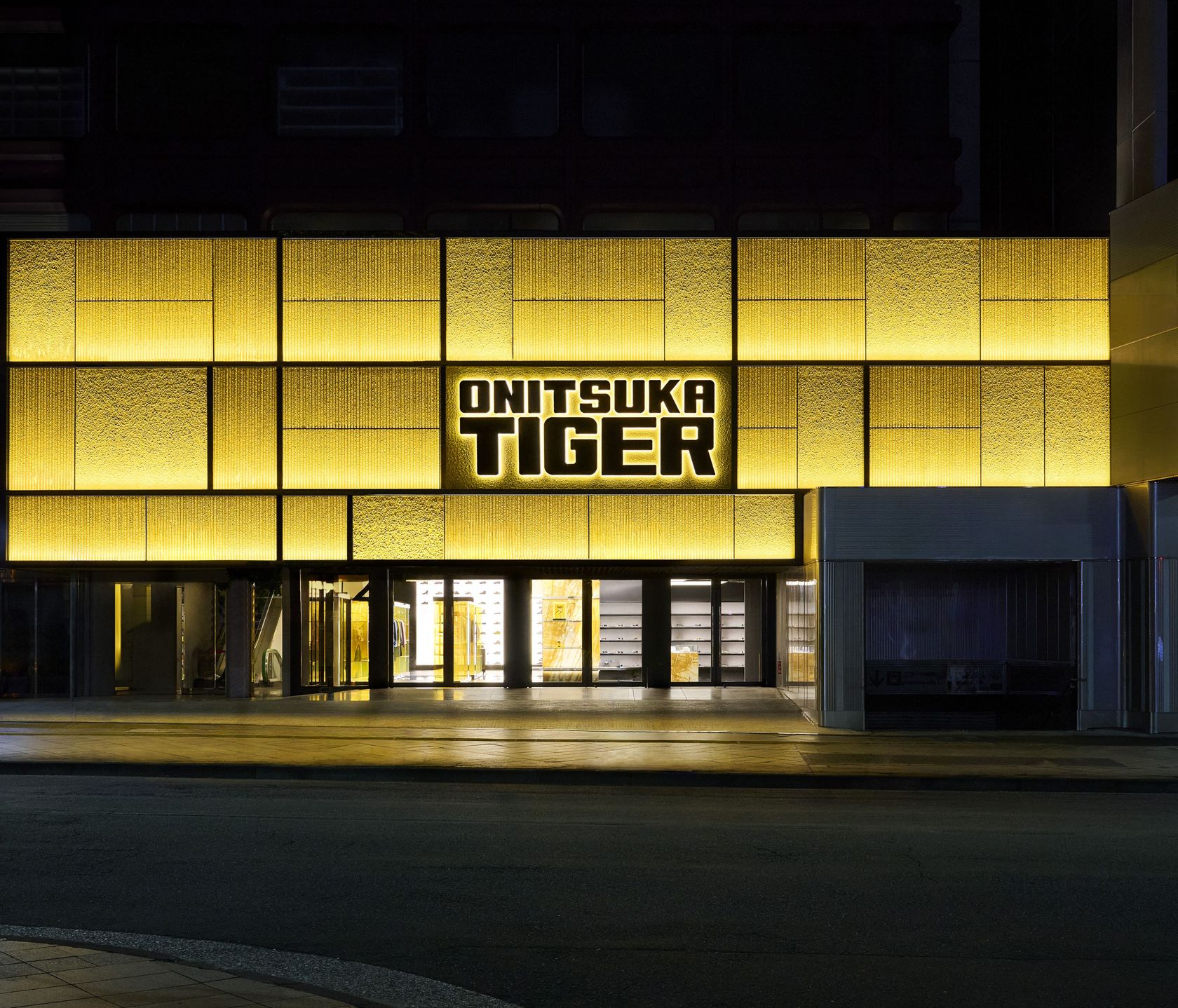 Fachada iluminada da flagship global da Onitsuka Tiger em Shinjuku, Tóquio