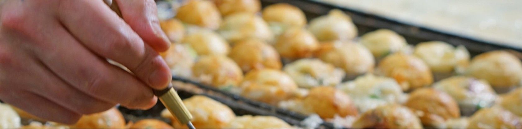 Takoyaki dourado sendo preparado na chapa