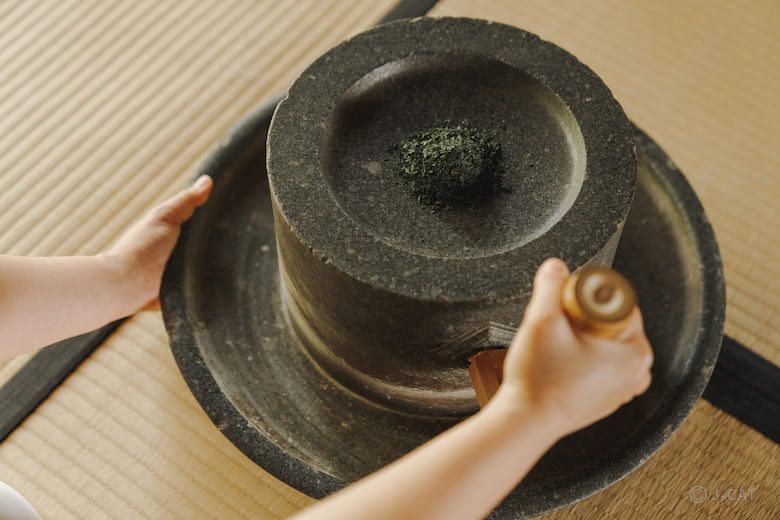 Tencha sendo moído lentamente em uma mó de pedra sobre o tatame