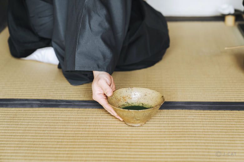 Mestre do chá serve uma tigela de matcha sobre o tatame